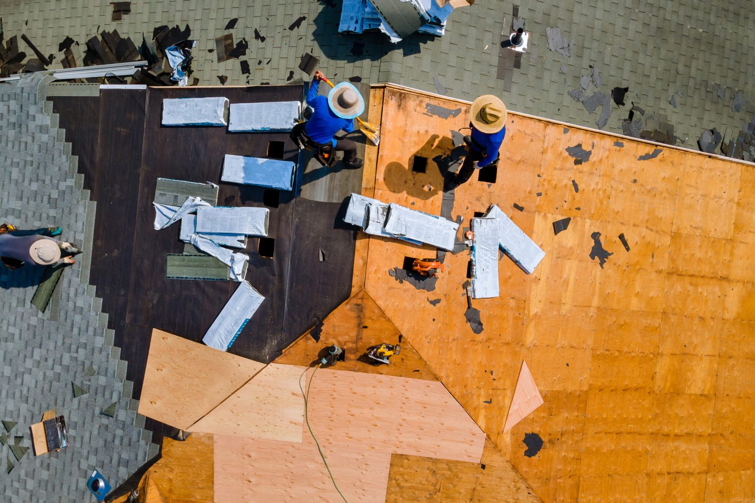 Aerial top view of construction roofer installing roof tiles at house building site at work installing roof shingles